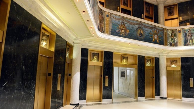 Interior building lobby with elevators and mural.