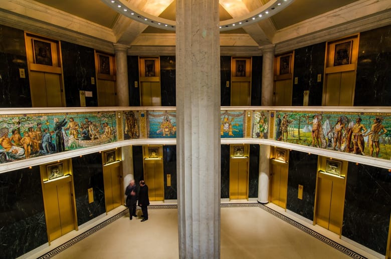 Interior building lobby with elevators and mural.