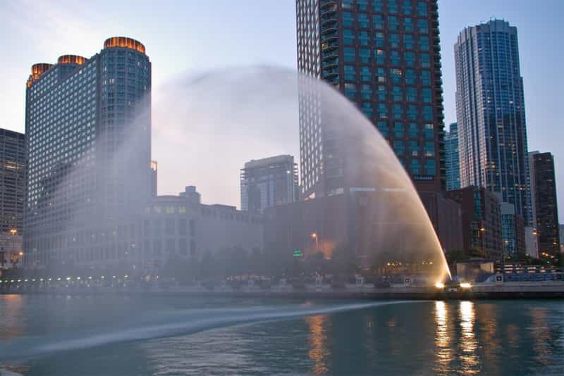 An arc of water shoots across the Chicago River