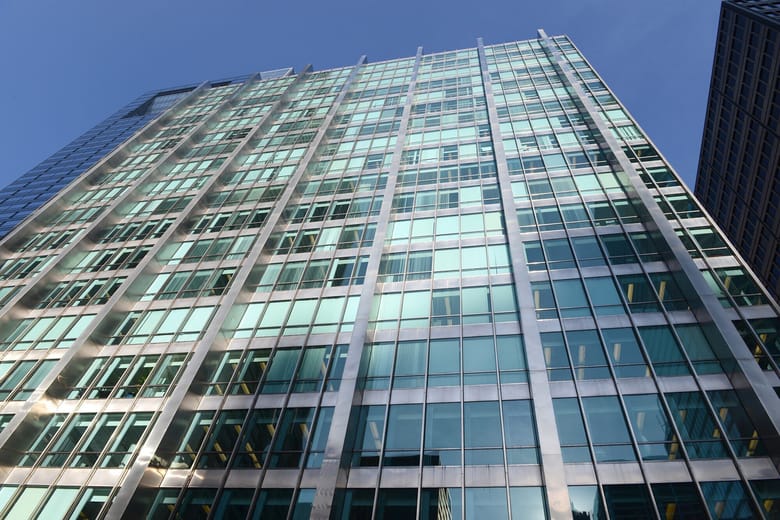 Exterior image looking up at a building covered in blue-green glass