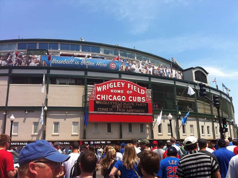 Image of the exterior of Wrigley Field with a large red sign that reads "Wrigley Field, home of the Chicago Cubs"