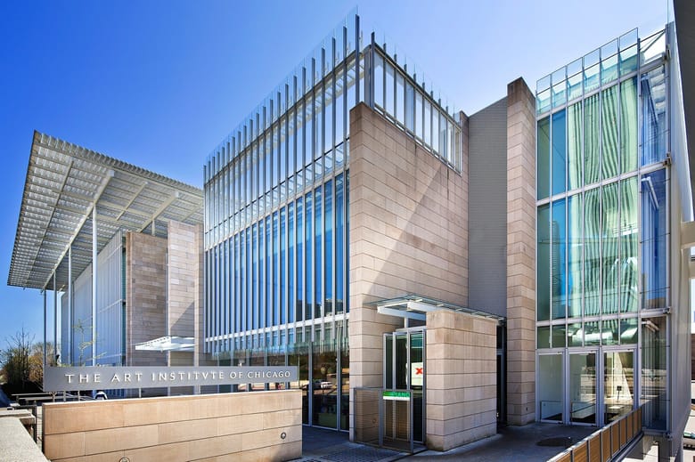 Image of a modern angular building with tan stone and a glass and metal facade.