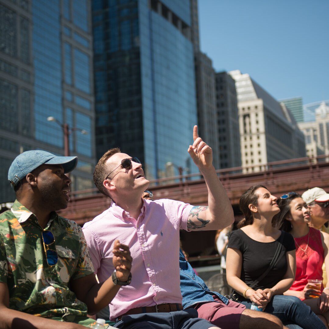 Guests smile and look up from boat on Chicago River