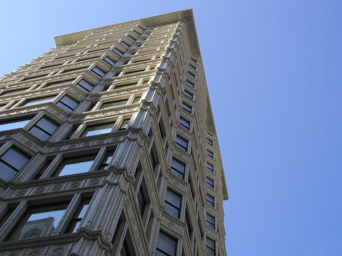 Image looking up at a white building with a decorative detailed exterior from below