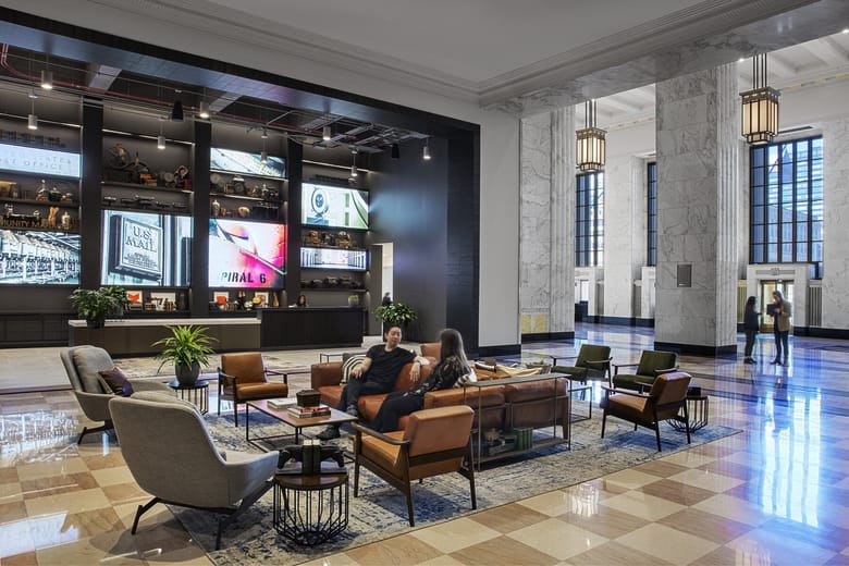 Image of a large hall with modern furniture and colorful screens on the far wall