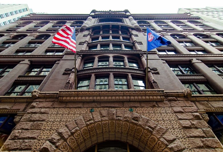 Exterior of brown stone building with United States flag