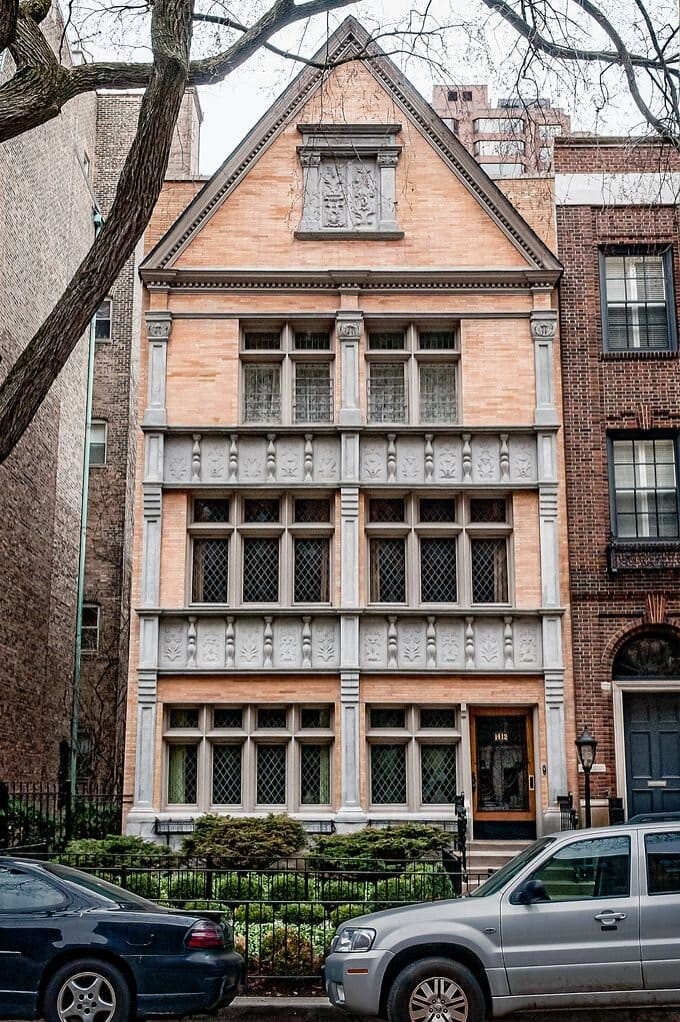 Four story orange brick home with a peaked roof.