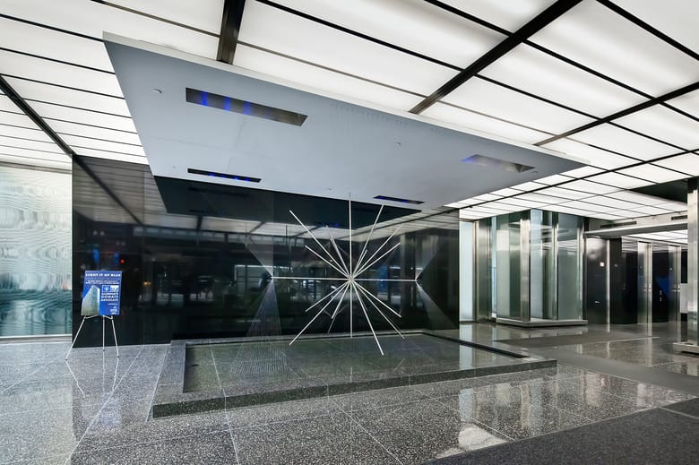 Interior shot of a lobby with black granite floors and a sculpture that has poles spiking out