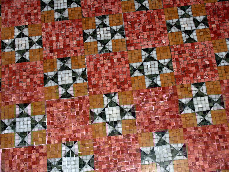 Close up of red black and white mosaic tile floor with quilt pattern