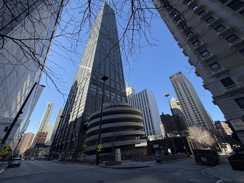 Image of a tall black building with a spiral tructure in the foreground.
