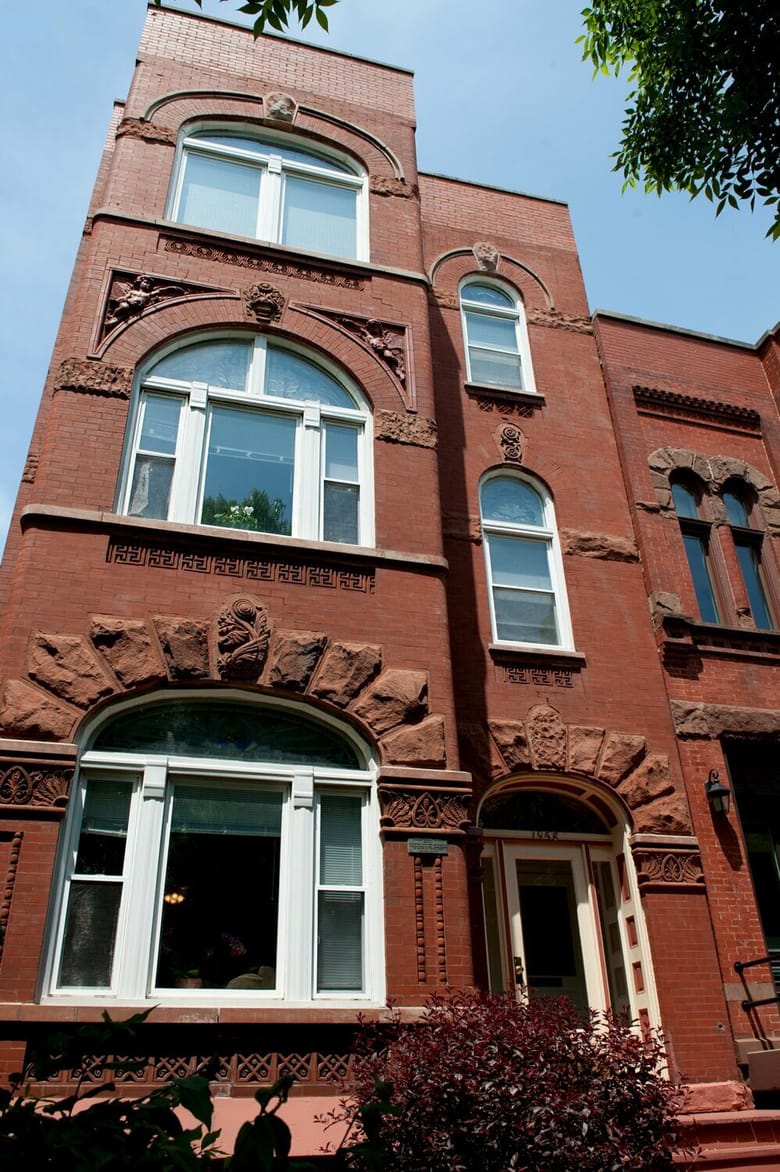 Three story red brick building with tall windows that are rounded at the top.